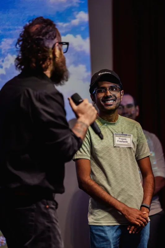 The host speaks to a community participant standing beside him.