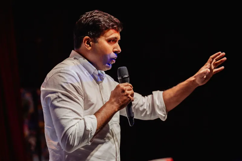 Taleeb Noormohamed makes a broad open-handed gesture near the end of his talk.