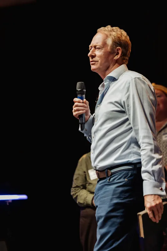 A community presenter addresses the room in a close side portrait.