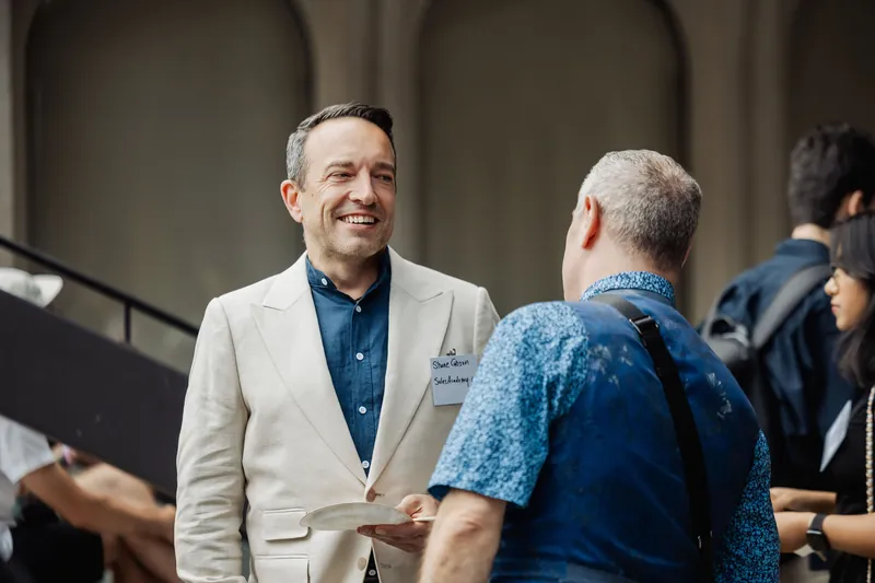 Two attendees laugh together while talking at the reception.