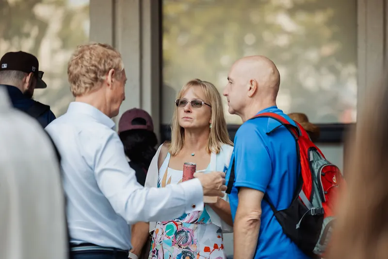 Three attendees talk together near the venue entrance.