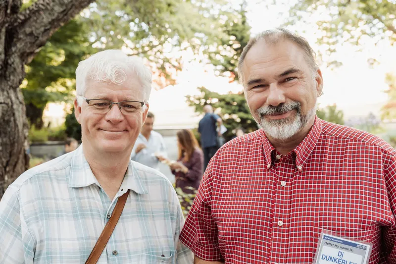 Two attendees pose side by side in the evening garden light.
