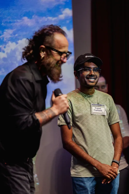 The host gestures toward a community participant during a brief introduction.