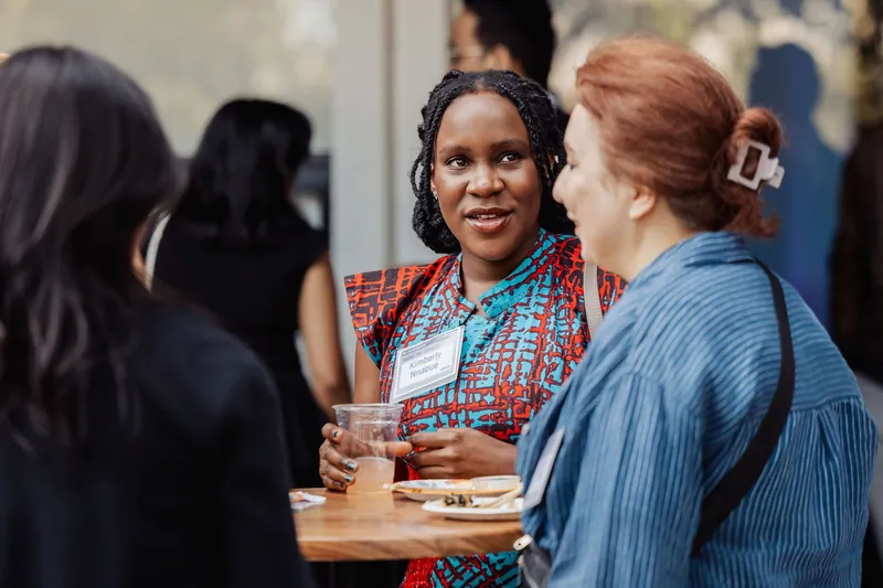 Two attendees speak face to face in the reception crowd.