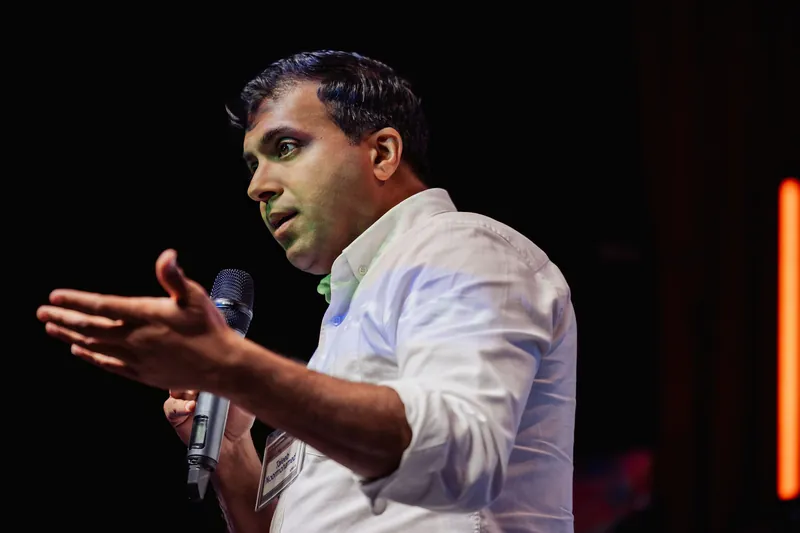 Taleeb Noormohamed reaches toward the audience while speaking.