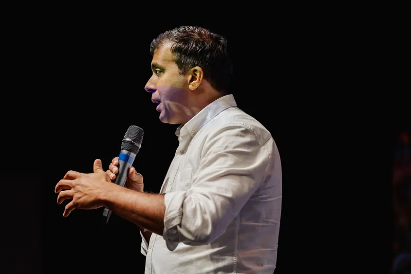 Taleeb Noormohamed speaks with both hands open in front of him.