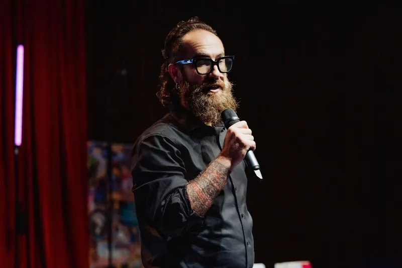 The host continues the welcome with a microphone in hand.