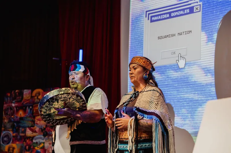 The cultural representatives continue the welcome beside the large stage display.