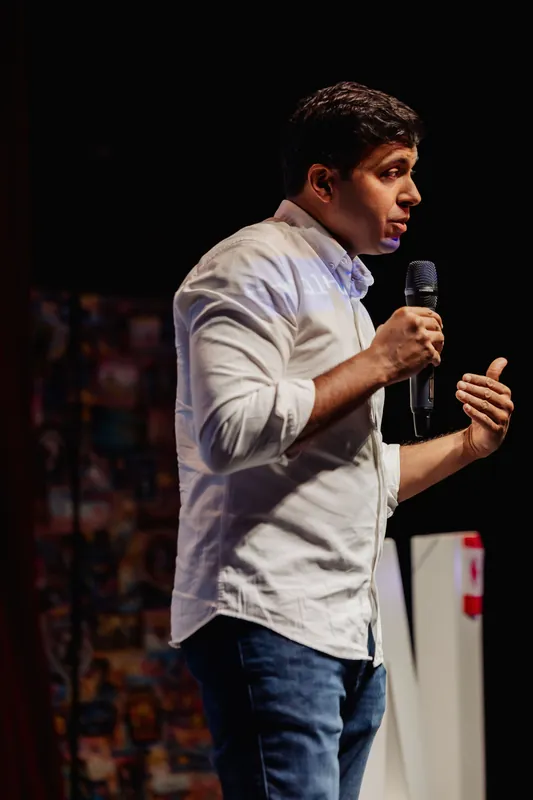 Taleeb Noormohamed gestures with both hands around the microphone.