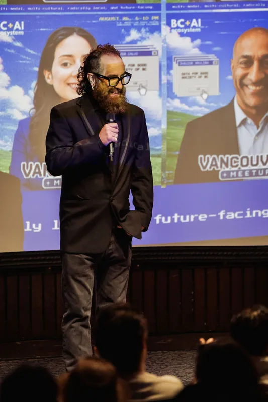 A close stage view frames the host's microphone against the meetup backdrop.