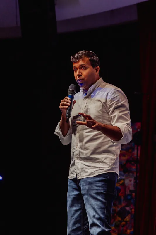 Taleeb Noormohamed addresses the room in a vertical full-stage view.