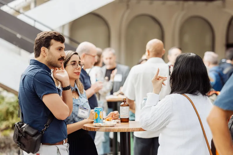 A small group talks around a standing table on the patio.
