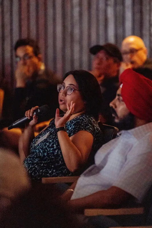 A seated attendee asks a question from the audience.