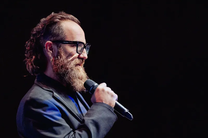The host pauses with the microphone during the welcome.