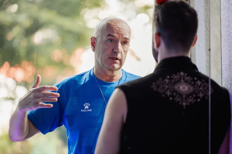 An attendee in a blue shirt gestures while speaking with another guest.