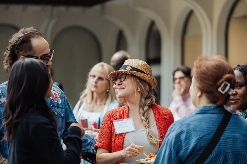 A cluster of attendees catches up beneath the venue's arches.