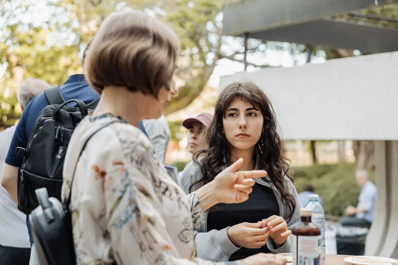 Two attendees talk beside a high-top table on the venue patio.