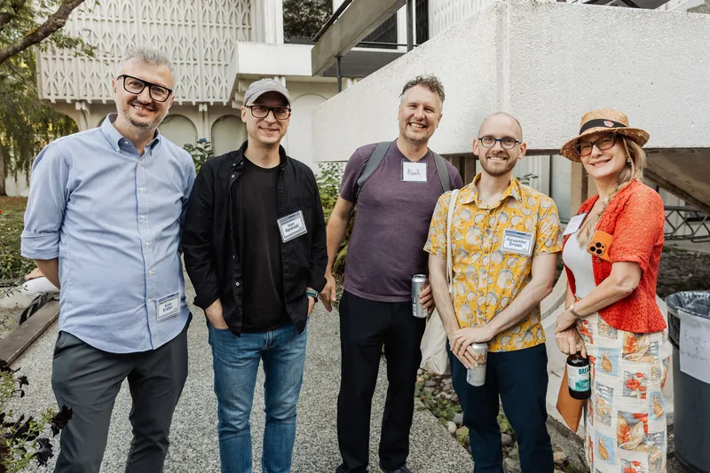 Five attendees gather for a relaxed group portrait in the garden.