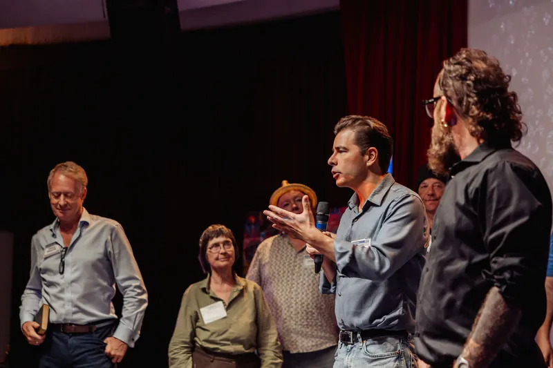 A community presenter speaks while fellow organizers stand behind him.