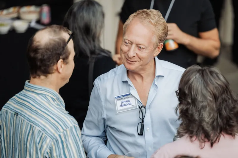 An attendee smiles warmly during a conversation in the reception crowd.