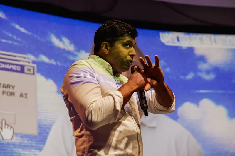 Taleeb Noormohamed listens as the host speaks beside him.