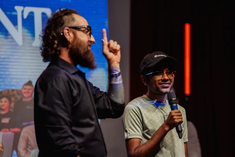 The host and a community participant share microphones onstage.