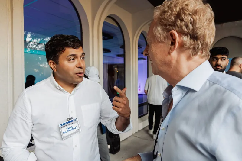 An attendee gestures while speaking with another guest near the auditorium.