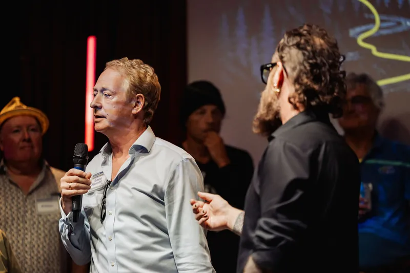 The community presenter and host face each other during an onstage handoff.
