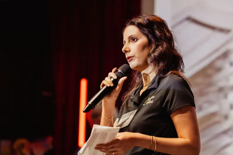A Data for Good presenter reads from notes while addressing the auditorium.
