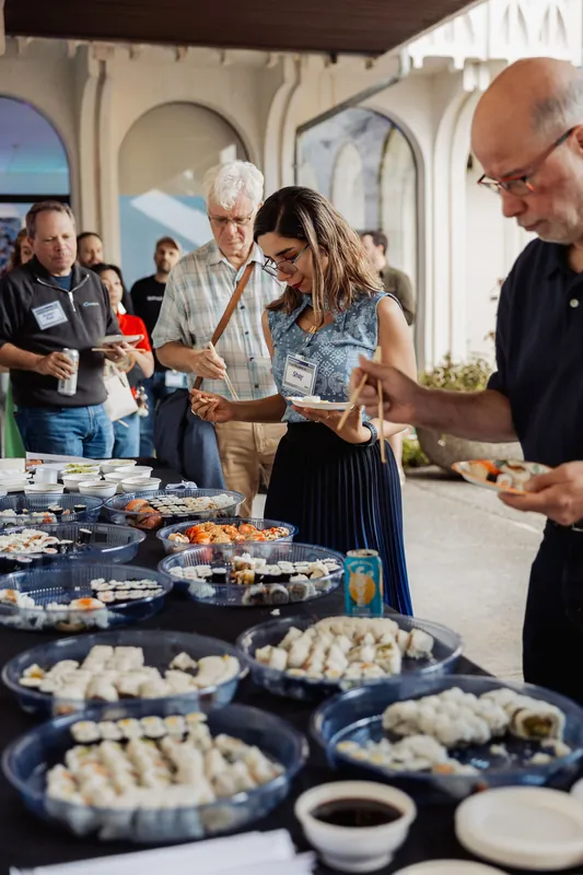 Attendees choose small bites from a buffet table at the outdoor reception.
