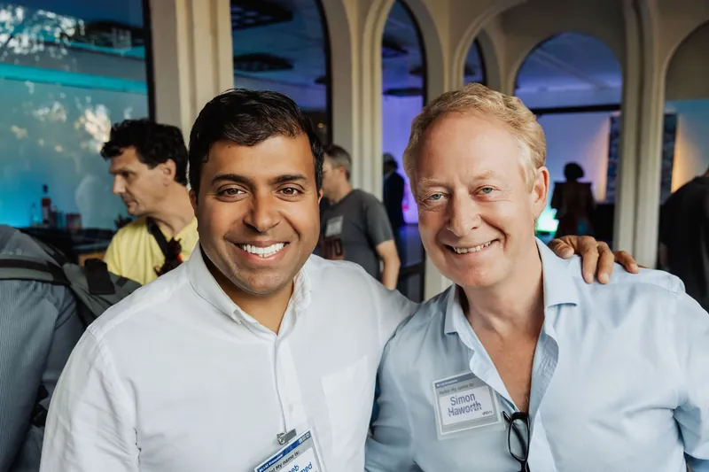 Two attendees smile together for a portrait inside the venue.