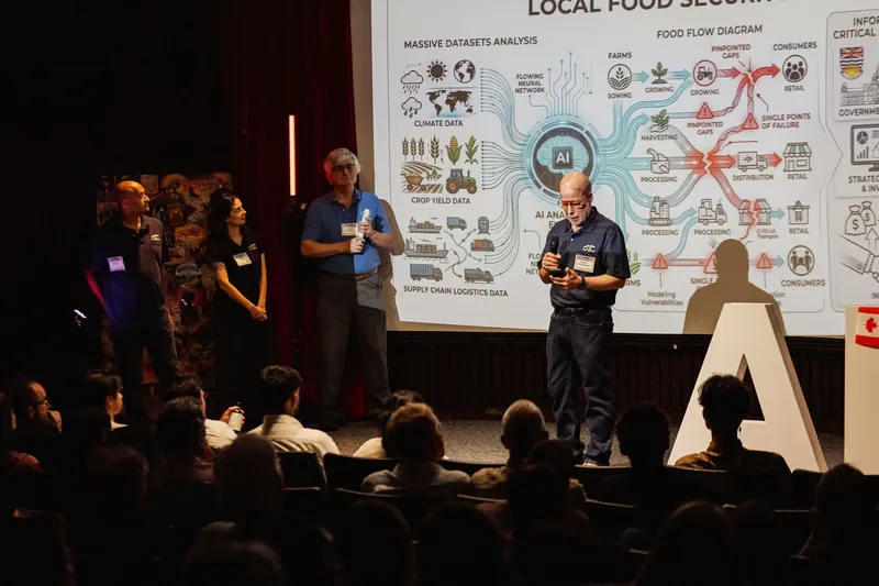 A presenter explains a local food systems project to the auditorium audience.