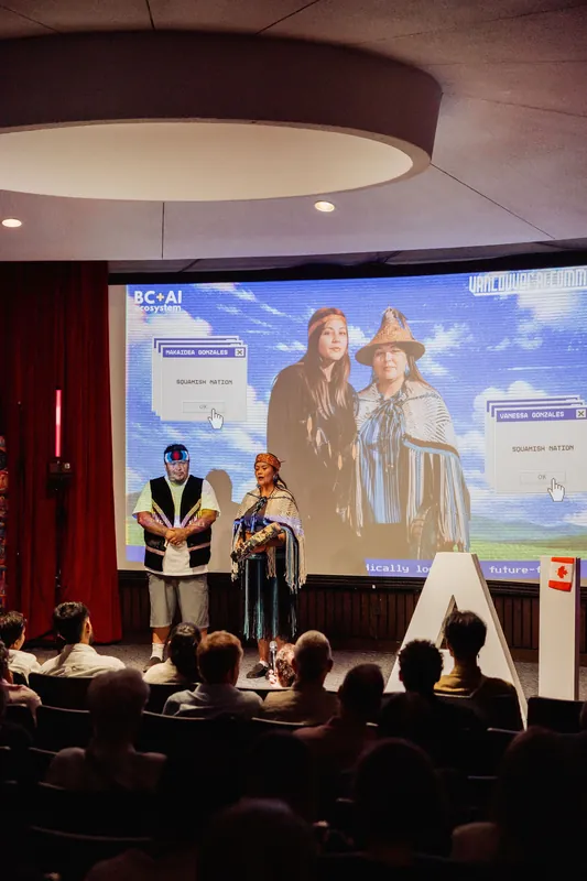 Two Indigenous cultural representatives stand together during the auditorium welcome.