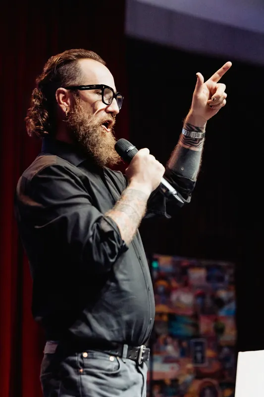 The host raises one hand to emphasize a point.