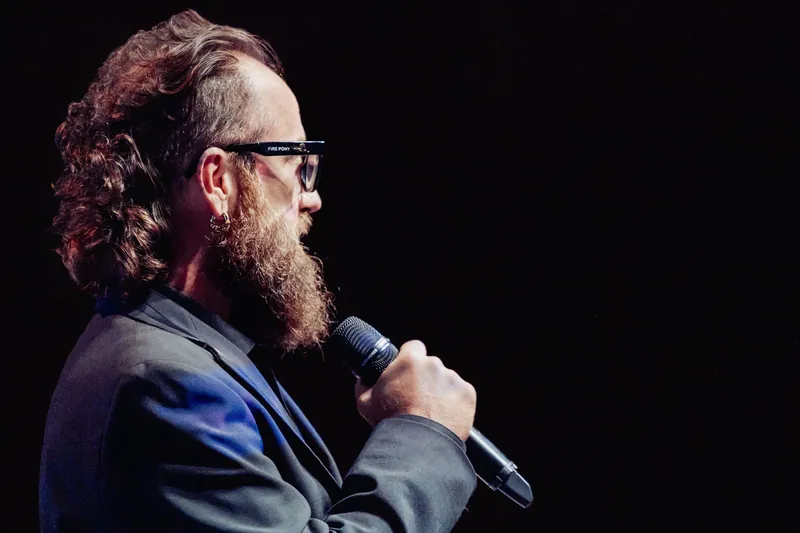 A side portrait shows the host speaking to the audience.