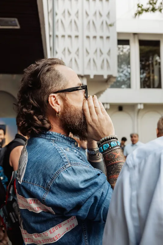 A bearded attendee watches the reception activity in profile.