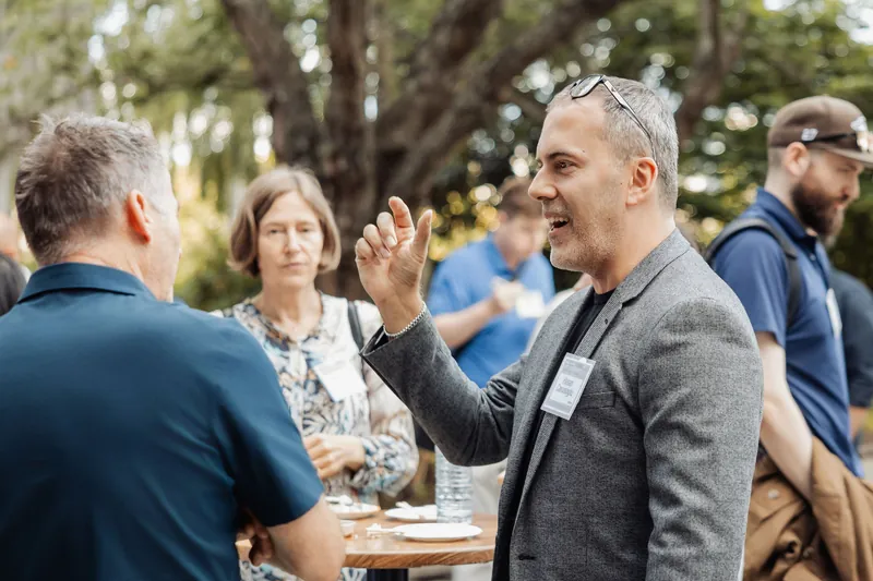 An attendee gestures during a lively conversation at an outdoor table.