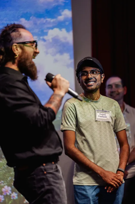The host and a community participant face each other onstage.