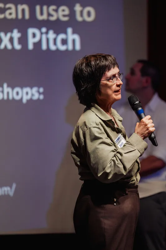 A community presenter speaks in front of a slide about a next pitch.