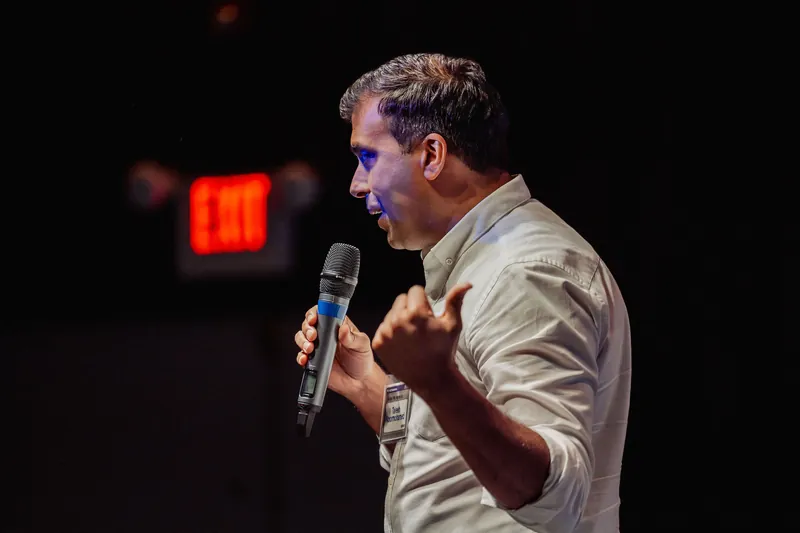 Taleeb Noormohamed gestures over his shoulder while speaking.