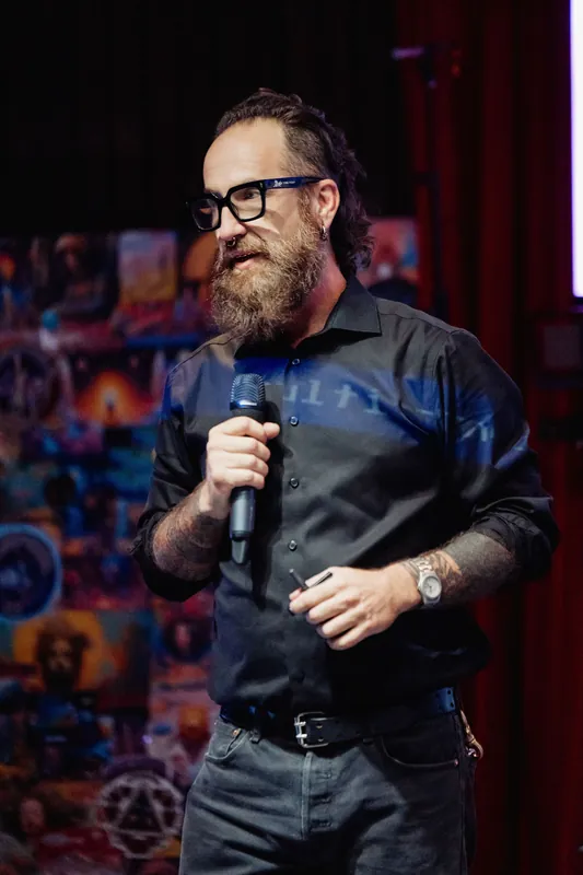 Stage light reflects across the host's shirt during the presentation.
