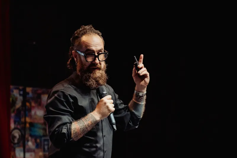 The host gives a thumbs-up while speaking to the audience.