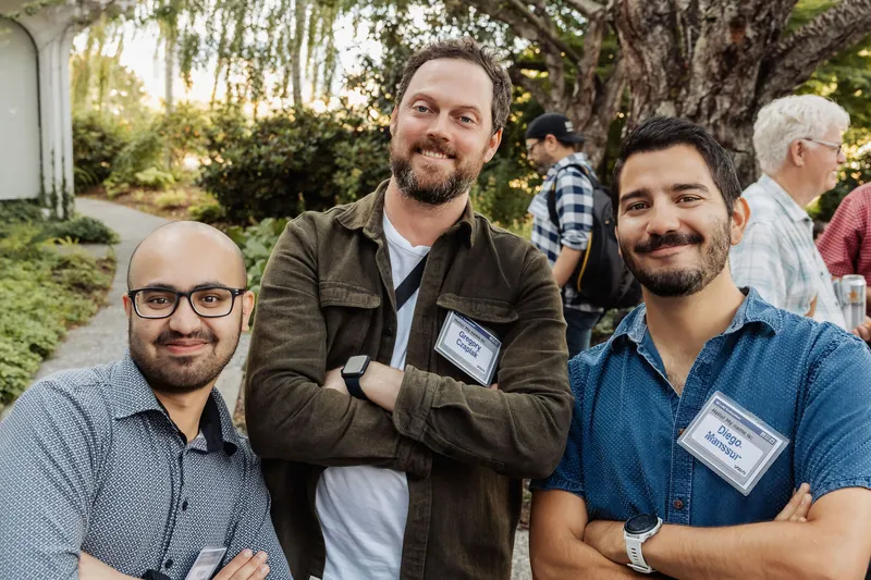 Three attendees pose together in the venue garden.