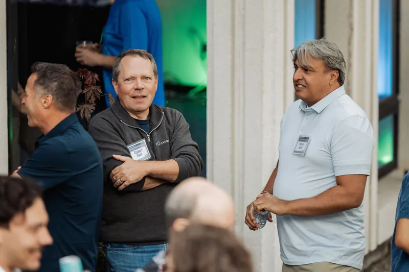 Two attendees converse beneath the venue's arched entryway.