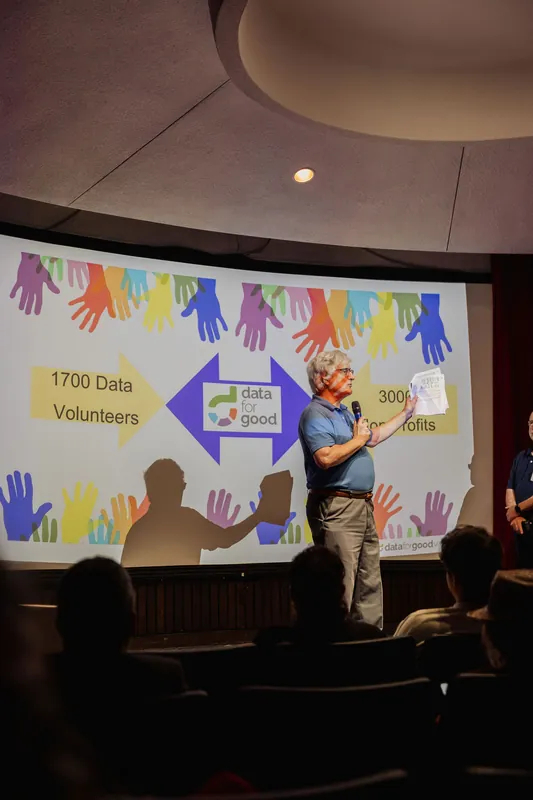A presenter explains a slide connecting 1,700 data volunteers with 3,000 nonprofits.