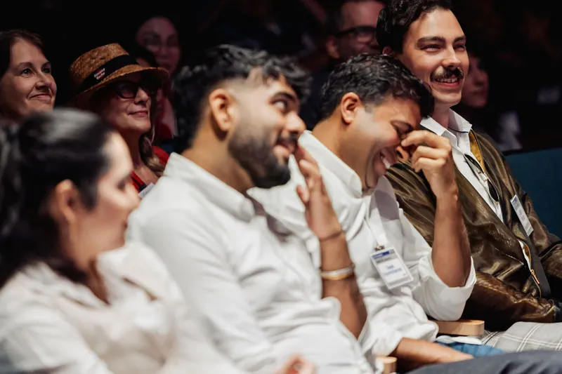 A row of audience members laughs during the community presentations.