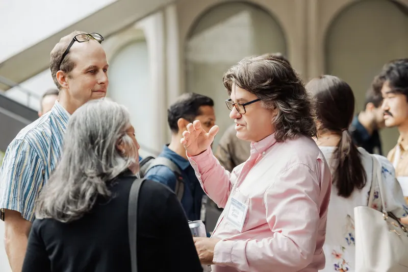 An attendee gestures during a conversation in the crowded patio reception.