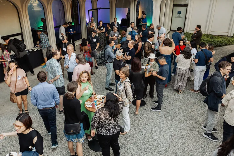 An overhead view shows a large reception crowd filling the venue courtyard.