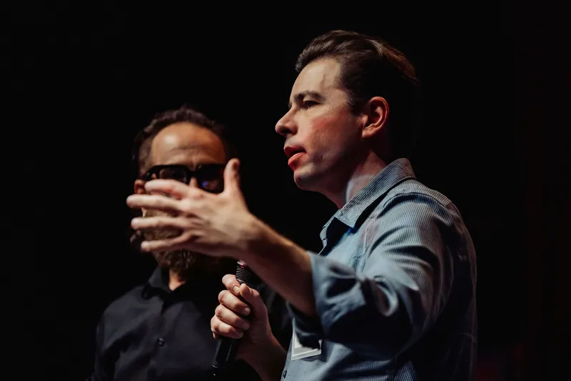 A community presenter and the host share the stage during a project announcement.