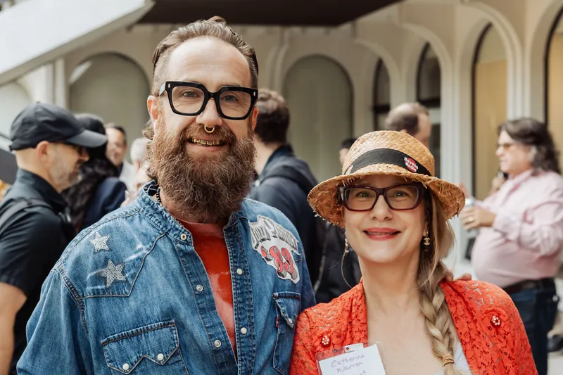 Two colourfully dressed attendees smile for a reception portrait.
